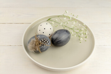Natural dyed grey Easter eggs in a plate on rustic wooden background. High angle view point.