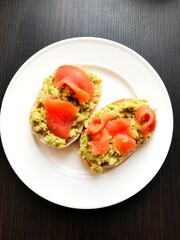 Brown bread sandwich with smoked salmon, avocado topped with chive and pepper