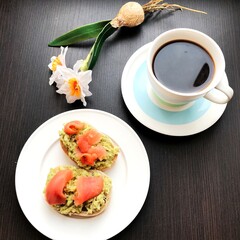 coffee and sandwiches with salmon and avocado on a plate.