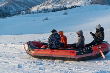 Tourists do snow rafting at sunny day. Altai Republic, Siberia, Russia.