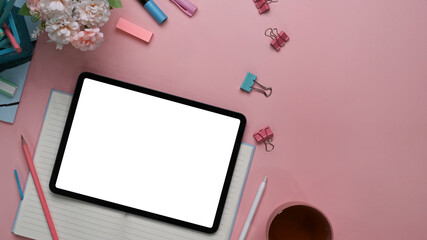 Above view of modern feminine  workspace with digital tablet, stylus pen, stationery, notebook and copy space on pink background.