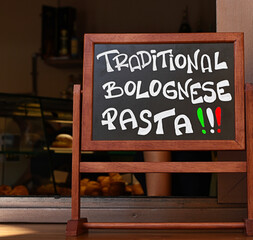 Blackboard with written text "Traditional Bolognese Pasta" in front of a restaurant in Bologna, Italy. Blackboard lettering.