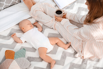 Mother with little baby sleeping on bed at home