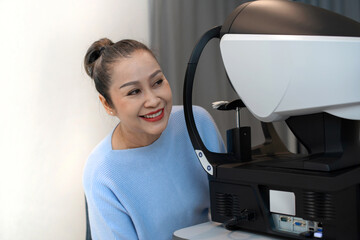 Asian senior woman with eye vision measurement machine in clinic, smiling with some one selective focus, diagnostic ophthalmology equipment