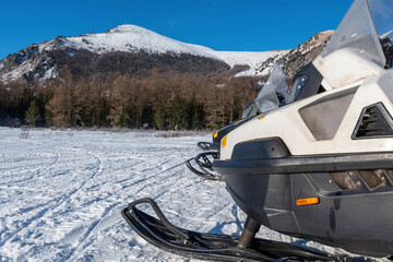 Two snowmobiles stand against snowy mountains. Multa lakes, Altai Republic, Russia.