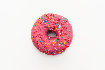 Pink donut decorated with colorful sprinkles isolated on white background. Flat lay. Top view