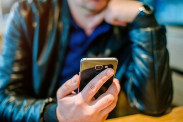 A man writes in her smartphone while sitting in a cafe
