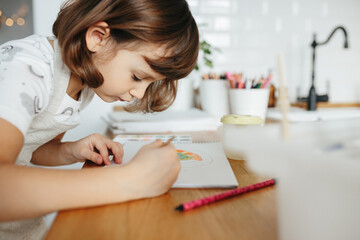 Kids painting watercolor rainbows at table at home