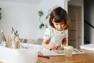 Kids painting watercolor rainbows at table at home