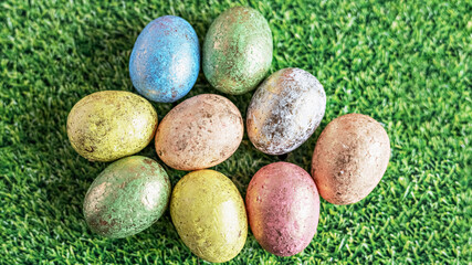 Easter eggs in pastel colors on a green background with grass texture. View from above