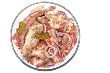 Boneless pork steak, sliced and marinated with onions, meat in a glass bowl, white isolated background, close-up.