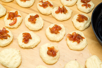 on a wooden table blanks with dough with jam for making buns, pies, donuts Cooking process with yeast dough with filling, close-up, top view