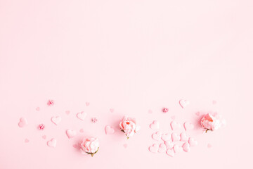 Valentine's Day background. Frame made of pink flowers, hearts on pastel pink background. Valentines day concept. Flat lay, top view, copy space