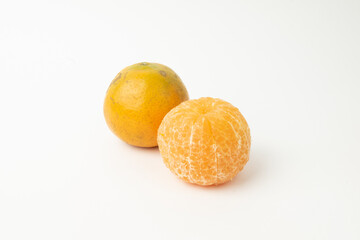 Orange fruit and peeled orange fruit on a white background