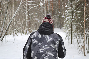 Fototapeta na wymiar Man goes in for winter sports - nordic walking, walks with sticks through a snowy forest. Active people in nature.