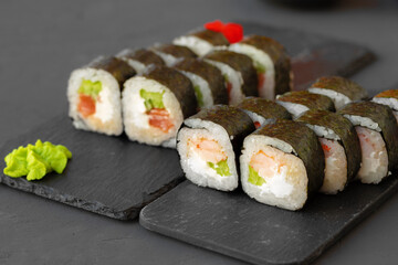 Maki sushi roll served on stone plate on gray background