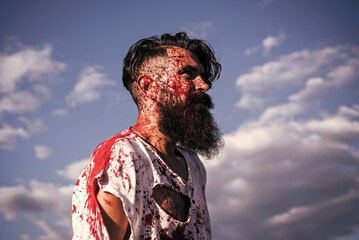Zombie hipster in torn tshirt with blood body on face. Halloween devil and horror. Man with red...