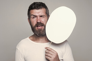 Hipster with winking face hold paper nameplate. Man on grey background, copy space. Feeling and...