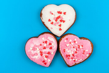 Fototapeta na wymiar two pink and one white heart-shaped gingerbreads on blue background