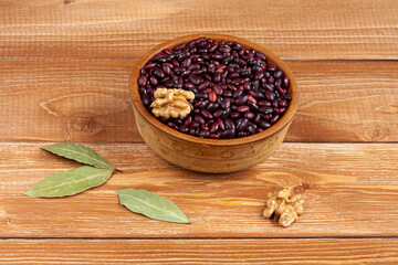 Fototapeta na wymiar haricot beans in a wooden bowl, walnuts and laurel leaves on brown wood boards