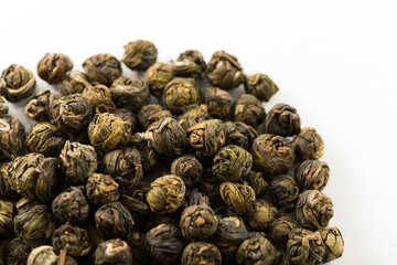 A pile of green jasmine pearl dried tea on a white background. Chinese traditional twisted tea