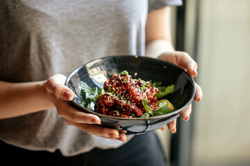 Girl holding a bowl of marinated chicken in spicy sauce with daikon 