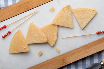 Cured sheep cheese. Cut into pieces on white marble and bread. Toothpicks for cheese. Top View.