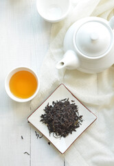 Finest quality blended tea powder. Black tea leaves and refreshing tea filled in a cup along with white tea pot. View from above.