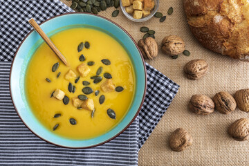 Close-up pumpkin cream in bowl. With croutons, pumpkin seeds and walnuts.