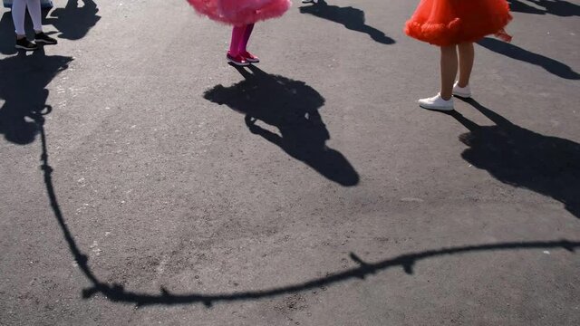 Children play rope on the street. View of shadows on the asphalt.
