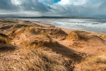 Sand dunes by the ocean. Blue cloudy sky. Nature background. Strandhill beach, Sligo, Ireland. Warm and sunny day