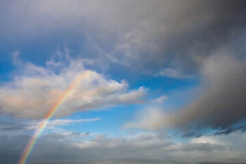 Fototapeta na wymiar Blue cloudy sky with rainbow. Nature background.
