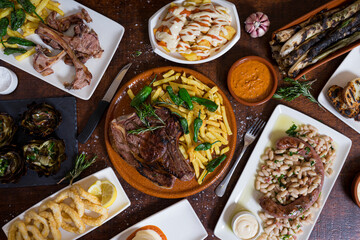Typical mixed Spanish dishes on dark brown wooden table. Top view