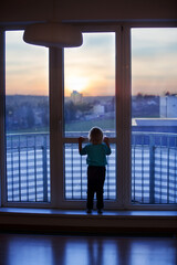 toddler child, sitting on the window on sunset
