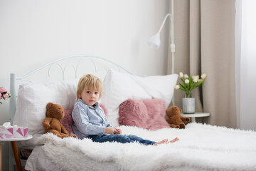 Obraz na płótnie Canvas Cute child, lying in bed, reading book