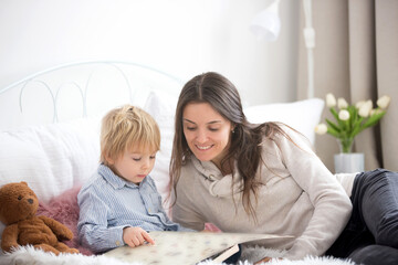 Mother and child, toddler boy, reading book in bed