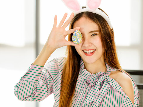 A beautiful young cute black long hair Asian woman covered her eyes with painted easter eggs