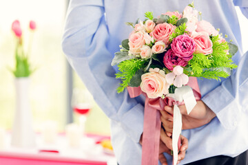 Man hiding roses bouquet behind him, ready to give for someone