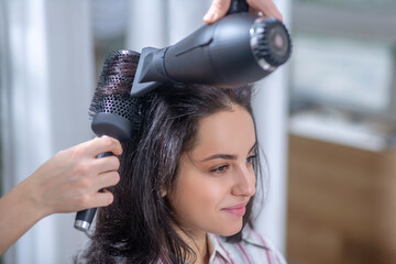 Dark-haired woman making hairstyling in a hair salon