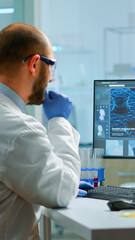 Man biologist checking DNA informations typing on pc in modern equipped laboratory. Scientists...