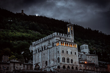 Night time view on illuminated building and cross on mountain in Gubbio