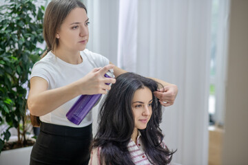 Fototapeta premium Young long-haired woman making hairstyling in a hair salon