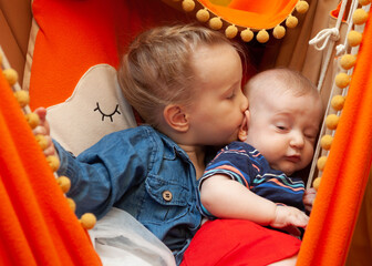 Sister is kissing her younger brother