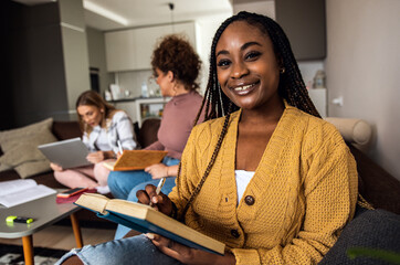 Portrait of female student learning at home with her friends.	