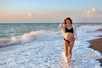 Fototapeta na wymiar young beautiful pregnant woman walking on the beach