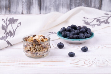Healthy breakfast with muesli and fresh blueberries on a white wooden table in a rustic style, close-up, horizontal