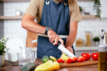 Portrait of handsome man cutting vegetables. Young man preparing salad.