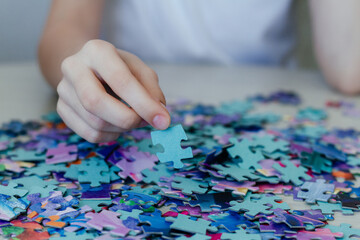 Fototapeta premium Caucasian girl collects puzzles on the table.