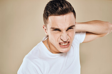 Obraz premium Man with displeased facial expression emotions white t-shirt gestures with hands beige background