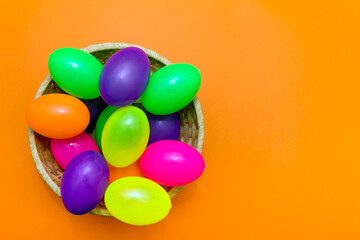 Fototapeta na wymiar Wicker basket with colorful Easter eggs on yellow background.Top view.